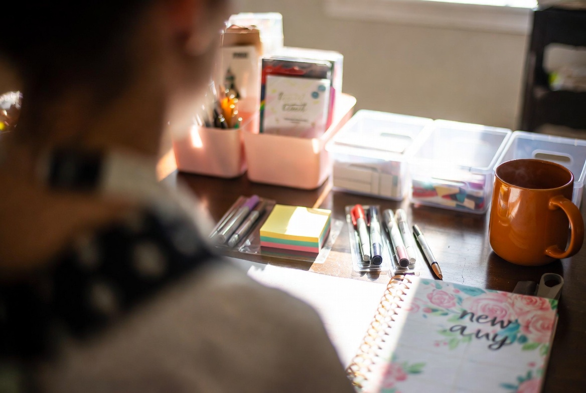 Student desk organized with sticky notes, pens, planner, and a warm mug