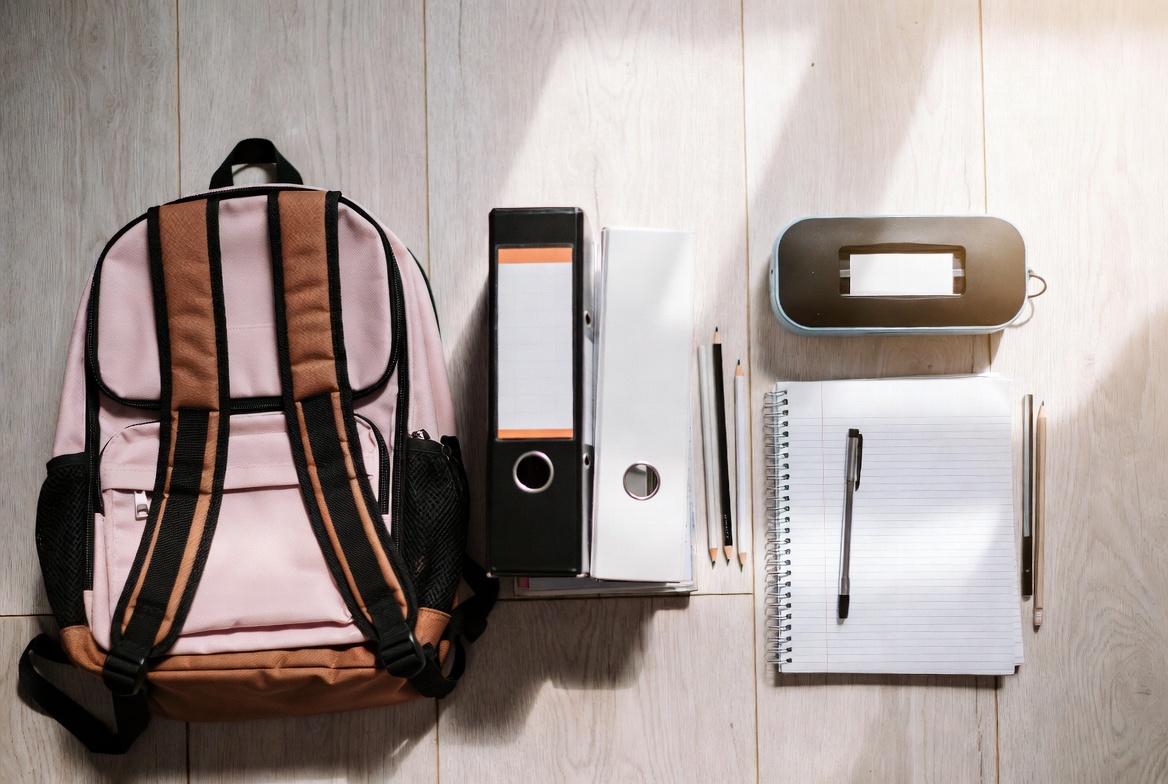 Back to school supplies laid out including backpack, binder, notebooks, and pencil case